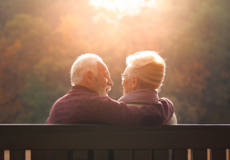 Ein älteres Paar sitzt auf der Bank und schaut sich an